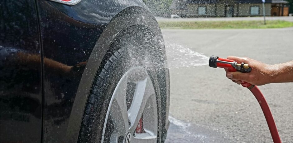 Reifen eines Autos werden mit Wasserschlauch abgespritzt