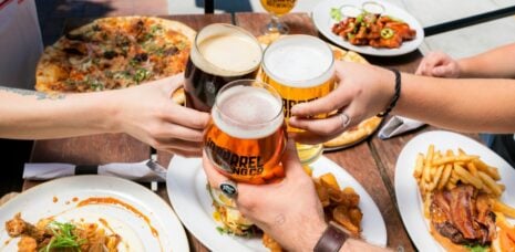 Leute, die im Freien Bier trinken und Pizza essen