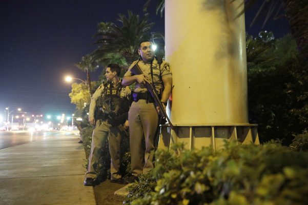 Zwei bewaffnete Polizisten gehen in Las Vegas während einer Schießerei nahe des Mandalay Bay Resorts und Casino auf dem Las Vegas Strip in Deckung. Foto: John Locher/dpa-Bildfunk