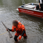 Ein Taucher der Feuerwehr holt eines der Gewehre aus der Saar. Foto: Polizei