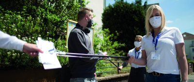 Mitarbeiter verteilen die kostenlosen Masken. Foto: SNS GmbH 2020